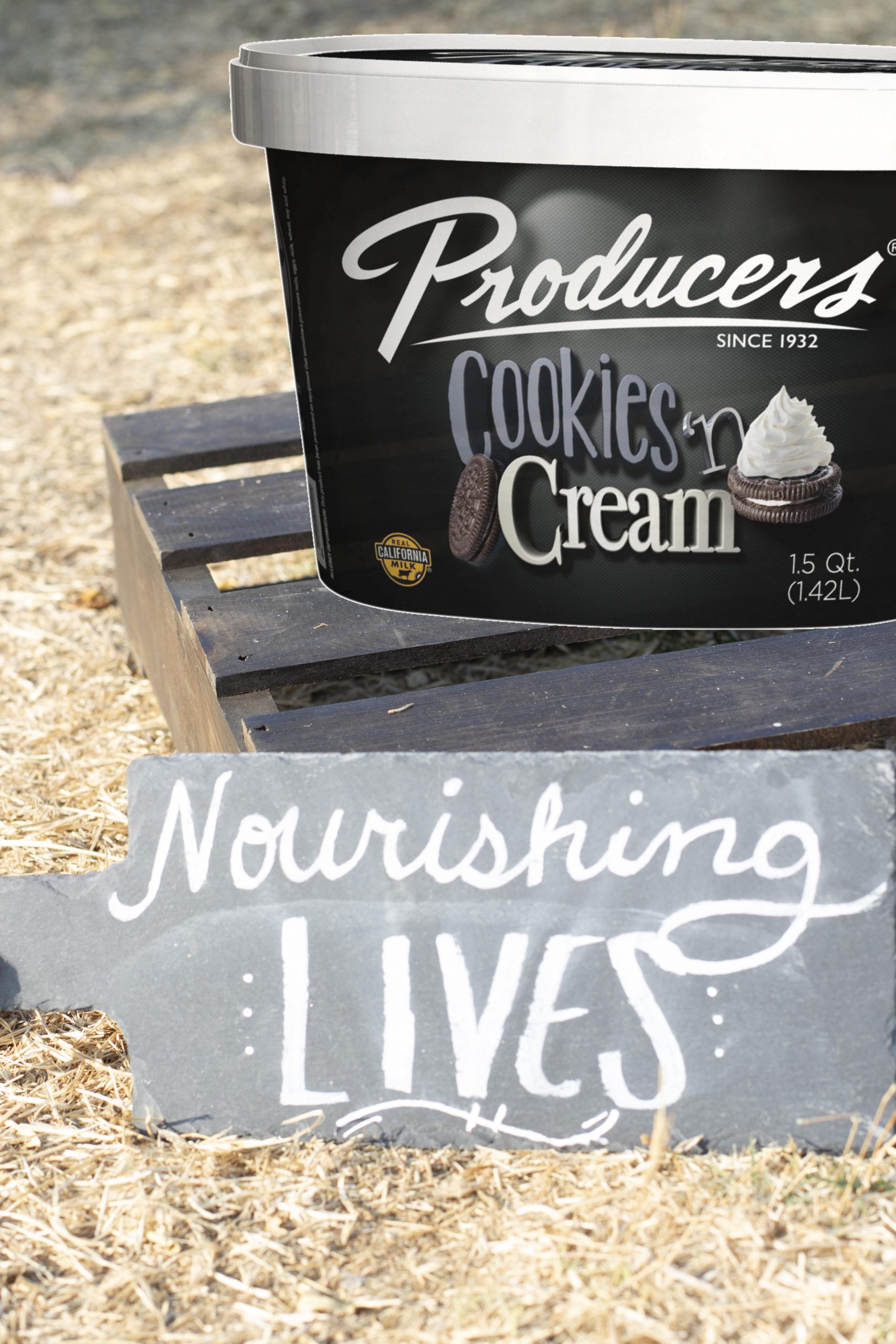 Cookies N Cream Producers Ice Cream sitting on wood in the middle of a hay field.