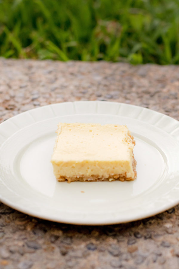 Sour cream lemon bar on a green plate outside in the backyard